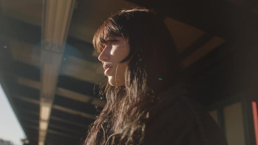 Portrait of a woman at a train station with sunlight reflecting on her face