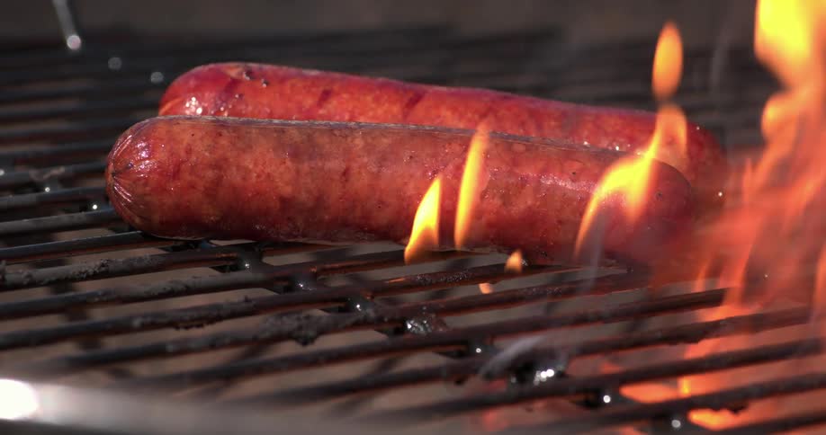 Hot dogs cook on a grill