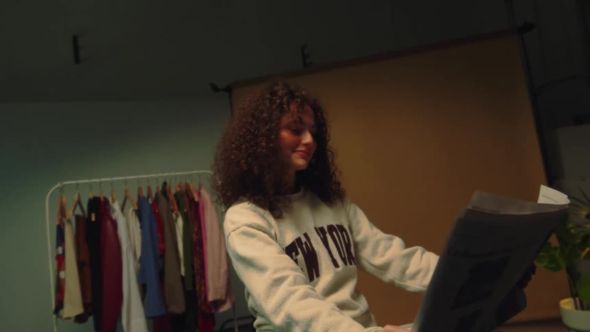 Portrait of a young woman with curly hair reading a newspaper