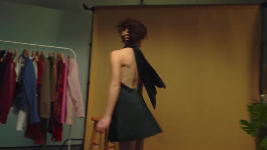 Model woman in a green dress spinning while walking in an indoor studio setting