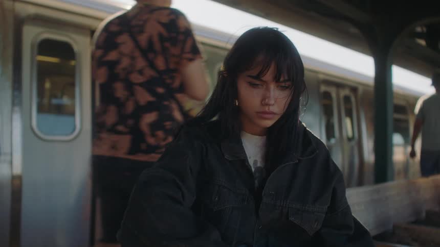 A sad young woman sitting at a train station