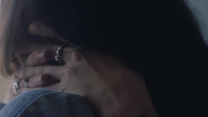 In a closeup a sad woman with rings and piercings is captured in a moment of contemplation reflecting a depth of emotion
