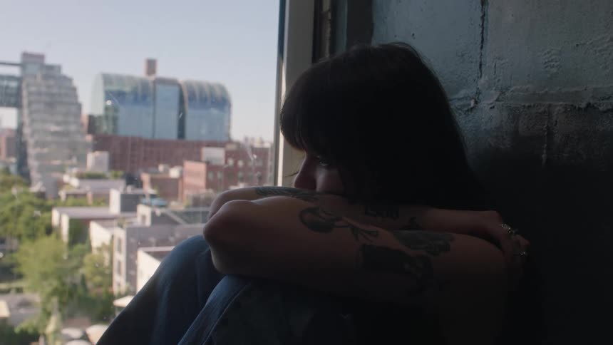 Sad girl looks at the city from the window