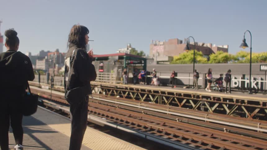 A girl smoking a cigarette while waiting for the train at the station