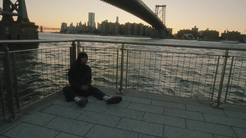 A woman sitting on the guardrail on the waterfront in the city