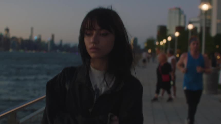 A girl walking along the beach in the city during dusk