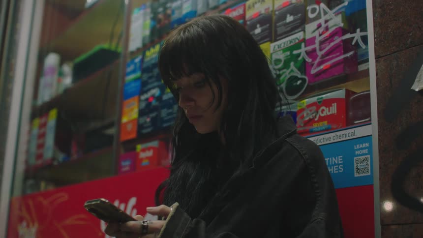 Teenager waits outside a store at night