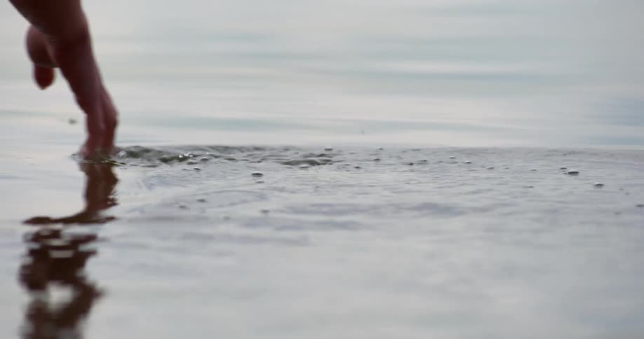 A hand runs through the calm water