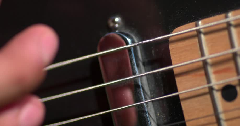 Close up of fingers plucking guitar strings