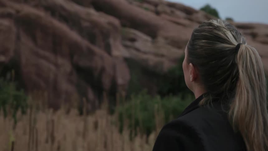 A woman is taking photographs with her phone of a mountain