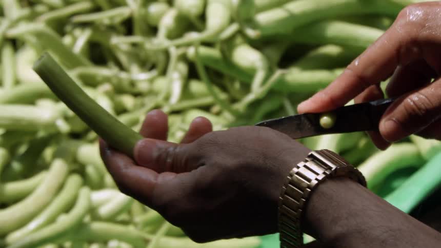 A man is cutting vegetables near a table