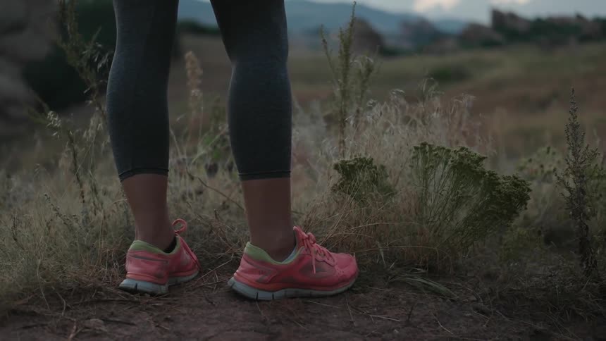 A woman is standing on a field wearing pink sneakers