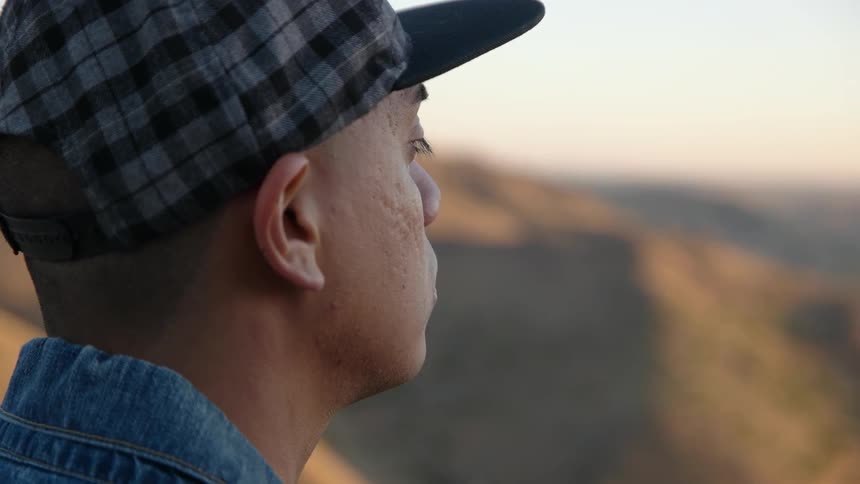 A man looks out of a range at sunset