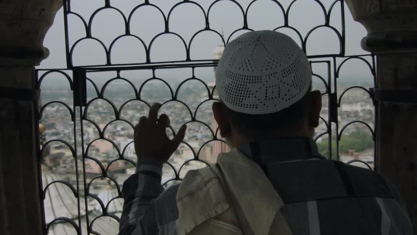 A man is leaning on a gated window before a city
