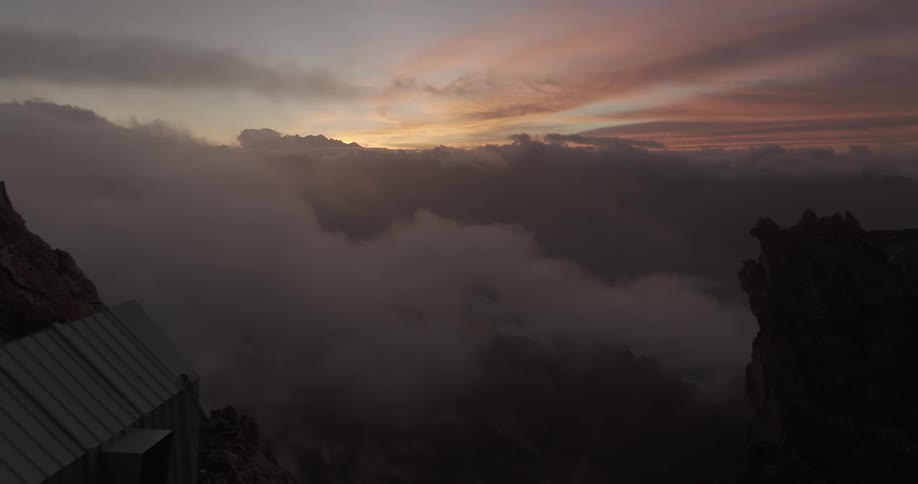 A small cabin on a huge mountain of rocks above the clouds