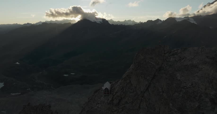 Person on the peak and cliffs of a mountain in a natural environment under a morning sky