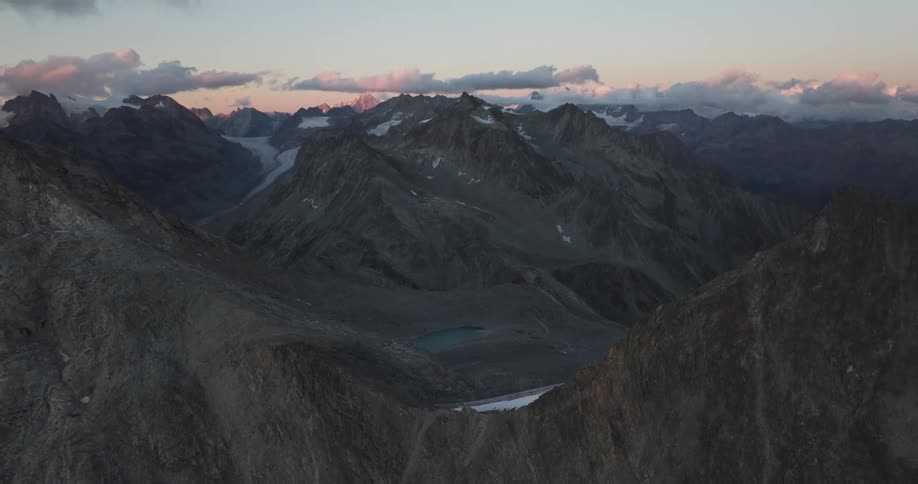 A river between jagged mountain peaks and a pinkish gray sky