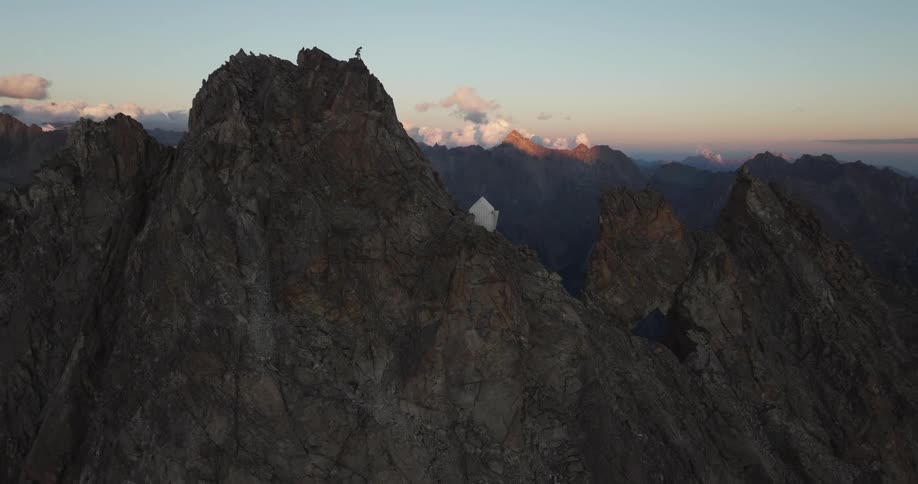 A man is perched at the top of the tall mountain