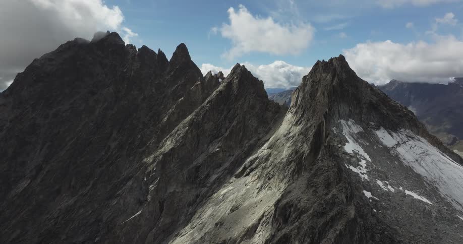A rocky and jagged mountain range is covered in snow under a cloudy sky