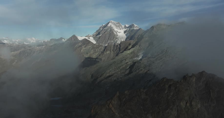 Snow covers the peak of a mountain within a rocky mountain range
