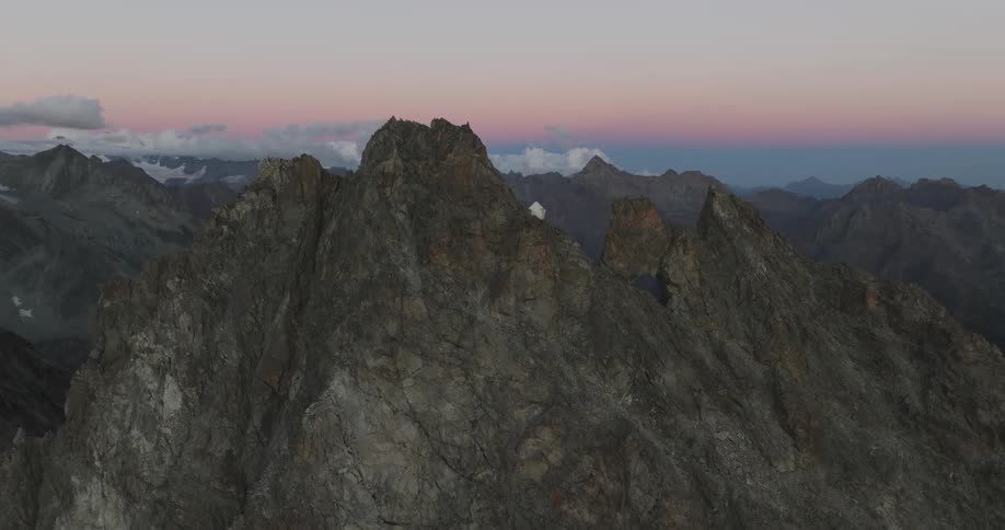 White house on the peak of jagged rocky mountain peak with purple sky