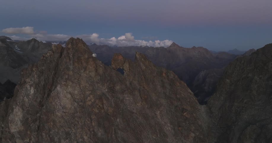 Aerial of the cabin on the peak of a mountain at dusk