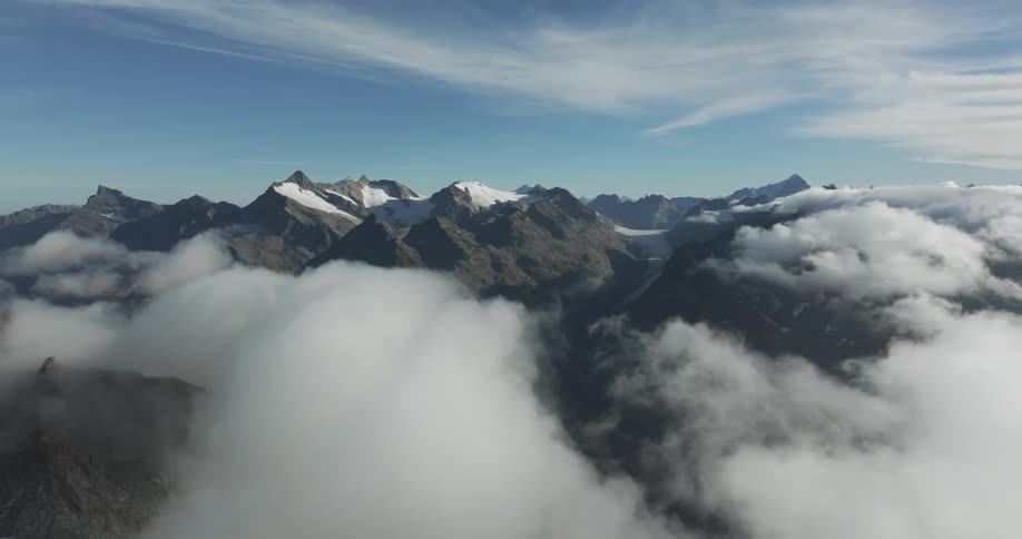 Aerial view of snowy mountain range and white clouds
