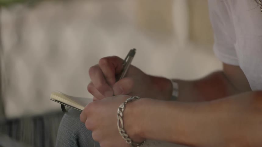 A man is behind a fence writing in a notebook