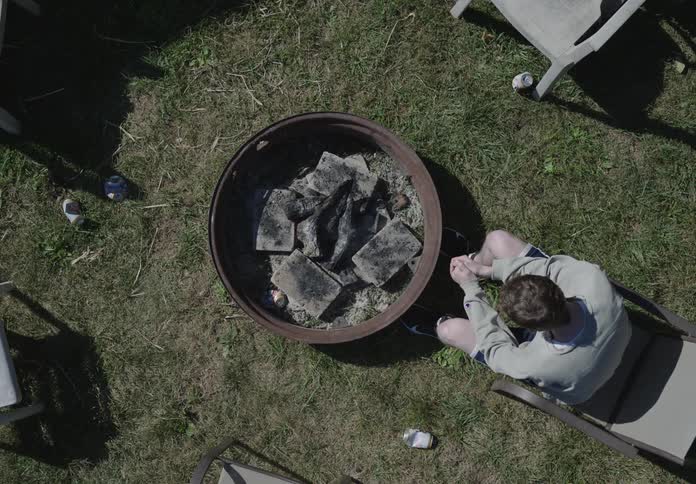 A man sitting beside a bowl with coal in it on a yard
