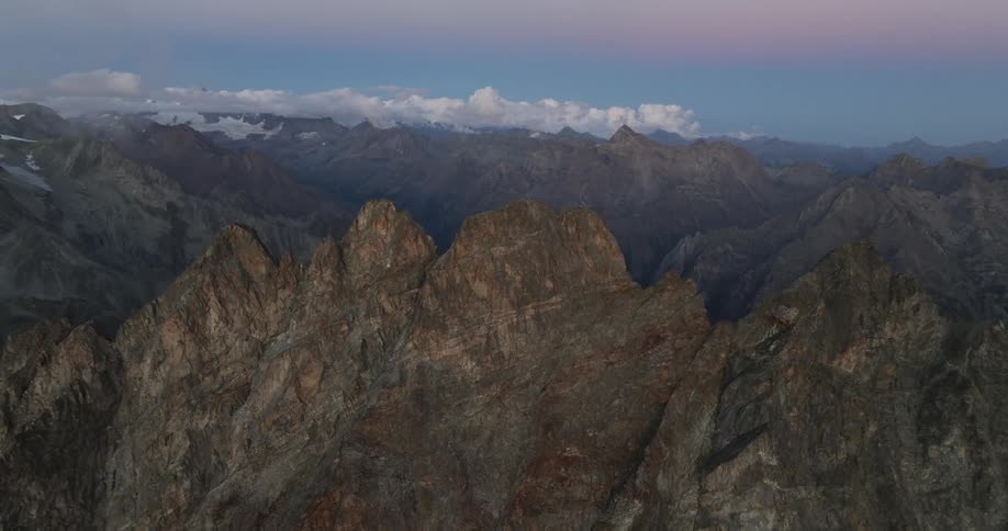 Aerial panorama of a mountain range and peaks with a purple morning sky