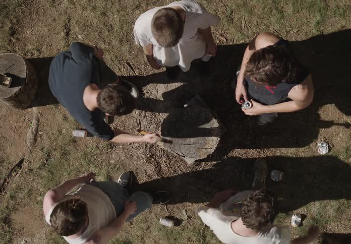 Group of friends around a tree stump playing with a hammer