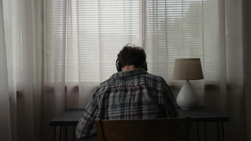 A man is wearing headphones sitting at a desk