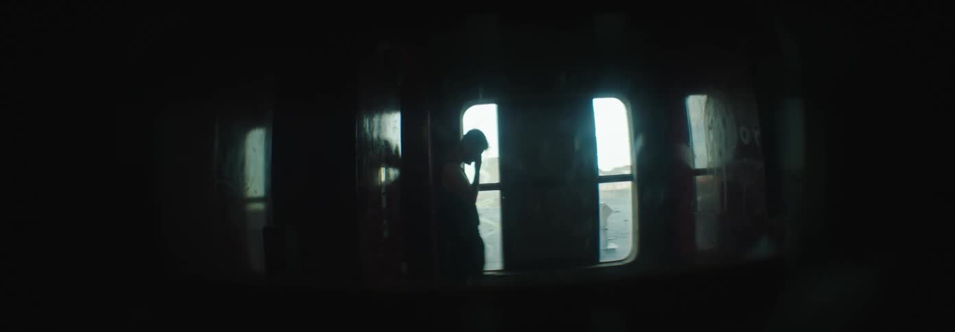 A man is standing behind the door in the dark