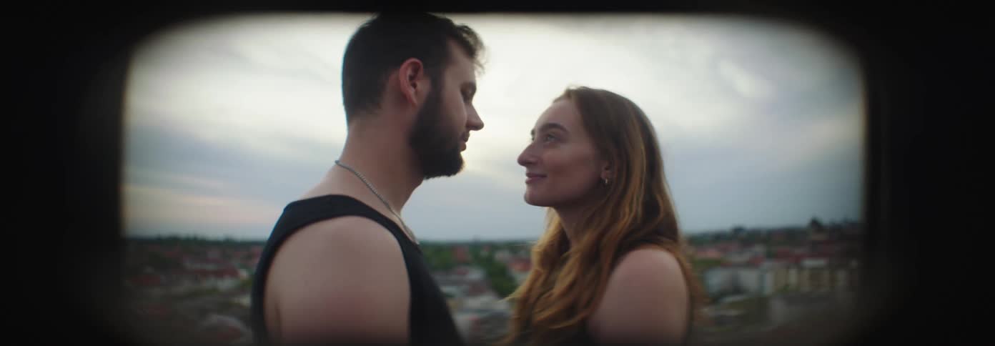Couple facing each other looking at each other with expressions of happiness under the daylight in a cloudy sky