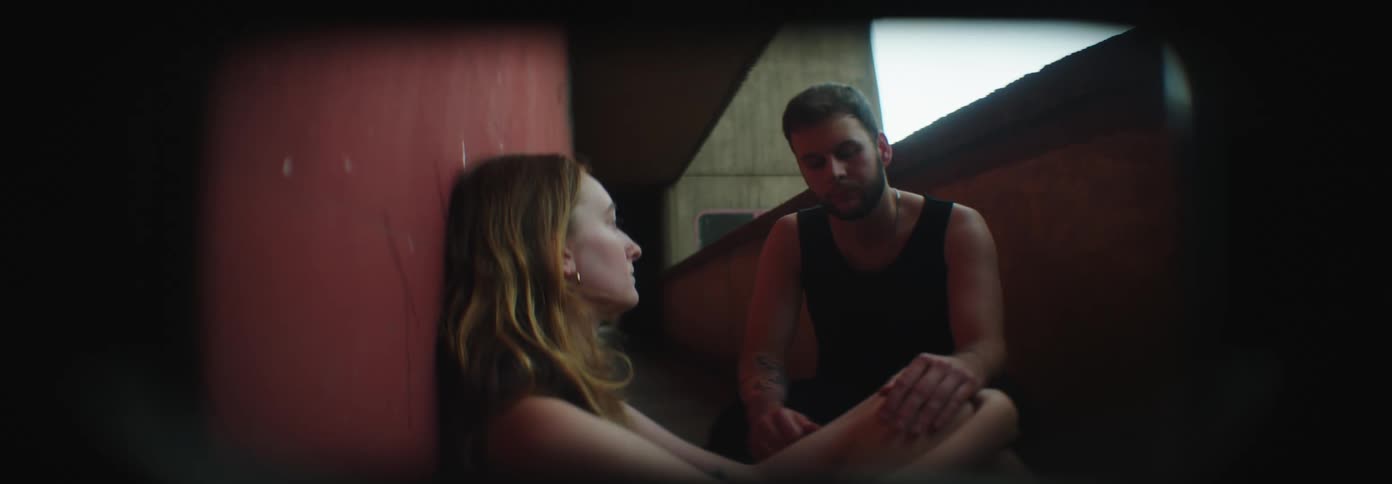 A man and woman sit and talk to each other outside of a building
