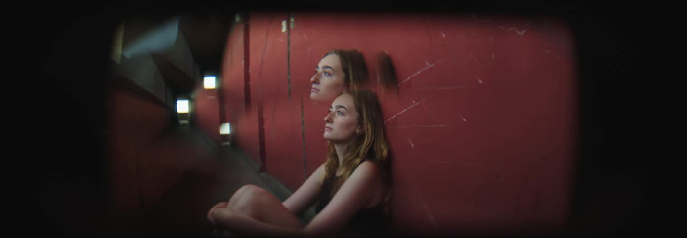 Young woman sitting on the hallway looks at the camera