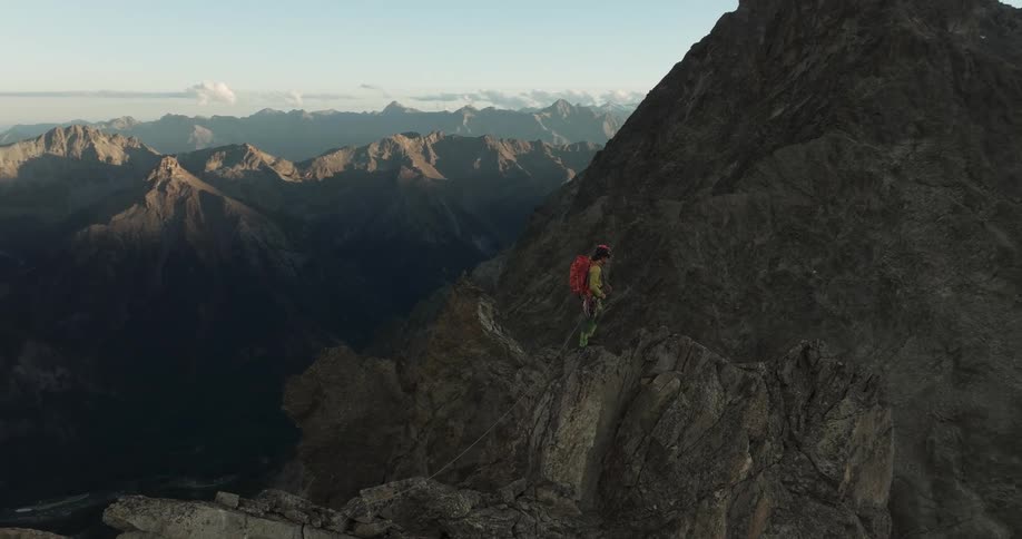 Woman climbing a cliff peak on a mountain in the morning