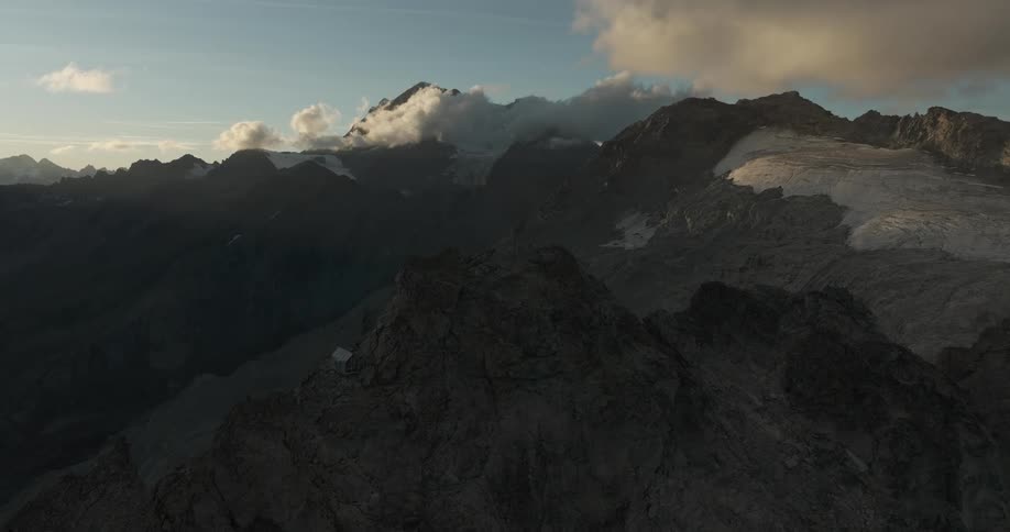 White house on a jagged peak in rocky mountain range at dawn