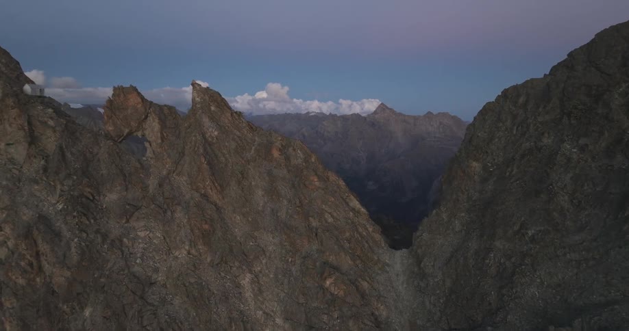 An aerial view of dark bare rocky mountains in the day