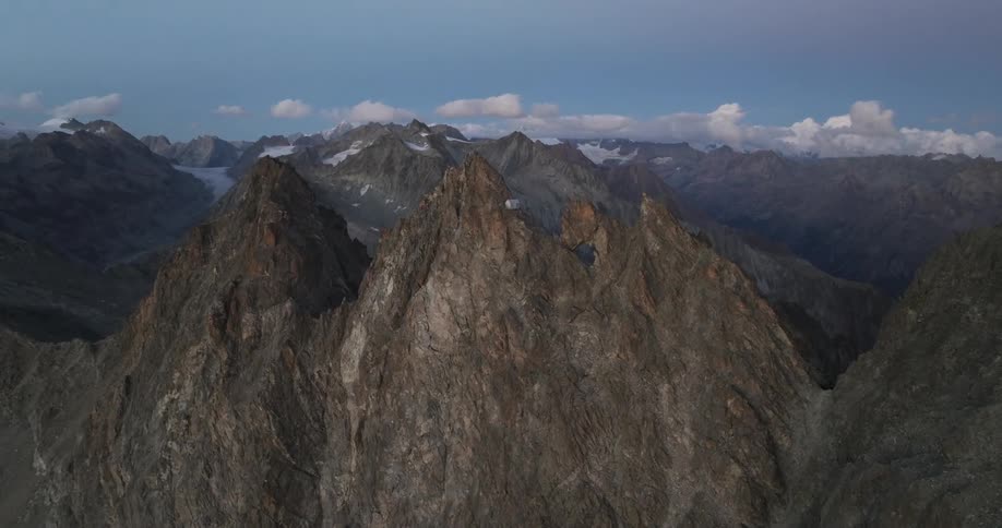Aerial of the rocky mountain with a small white cabin at the top