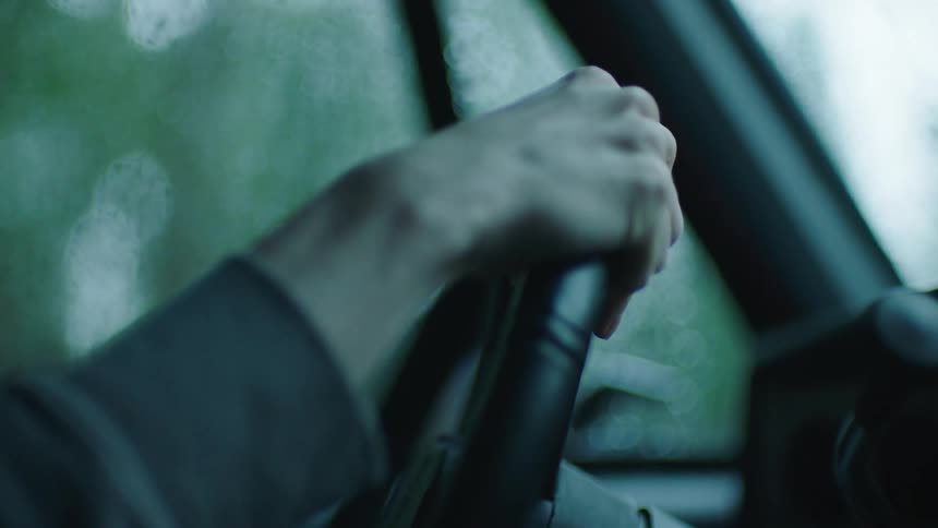 Closeup of hands turning the steering wheel and the car moving in reverse