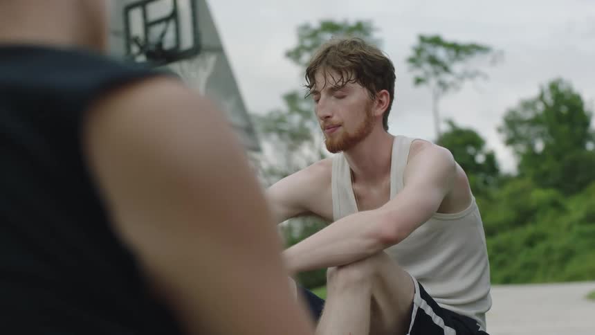 Young tired friends talking after playing basketball