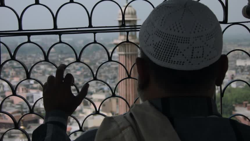 A man looks through a window grate to the city below