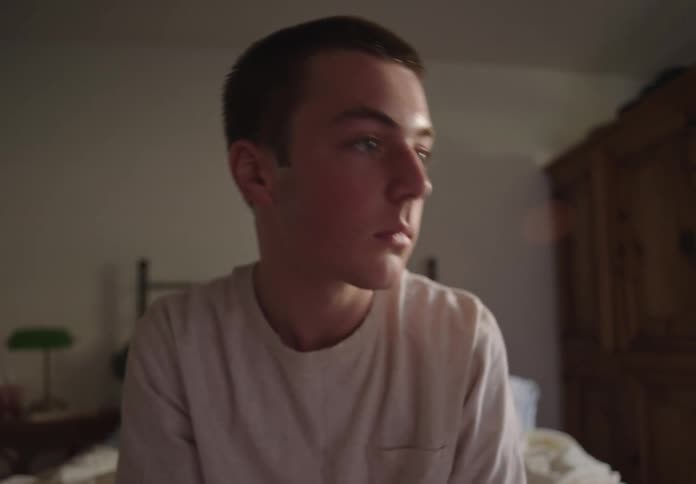 A teenager is sitting on his bed