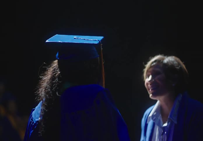 A graduate receiving her diploma in an auditorium