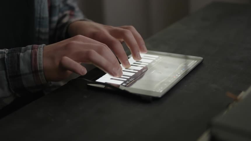 A person plays piano on a tablet