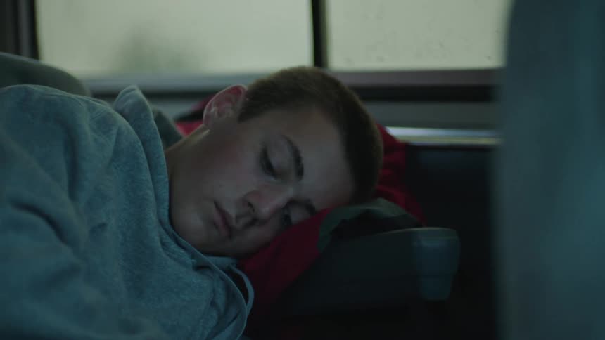 Portrait of a teenager sleeping inside a car