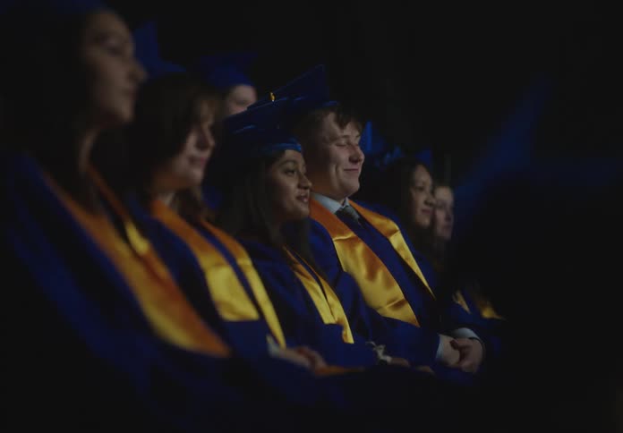 View of teenagers sitting on bleachers while talking and subsequently clapping their hands