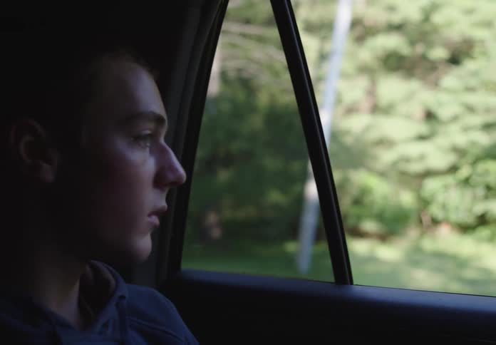 A sad teenager on a journey in a car