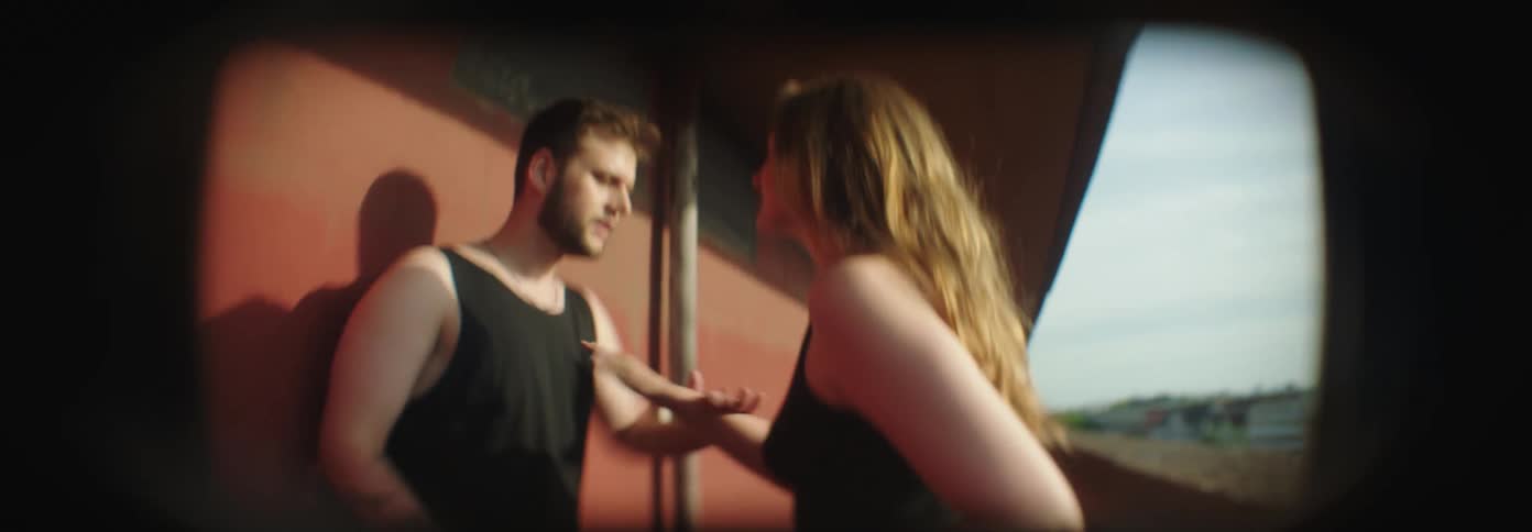 Woman arguing with a man pushing him against the wall in a corridor